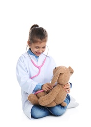 Cute child playing doctor with stuffed toy on white background