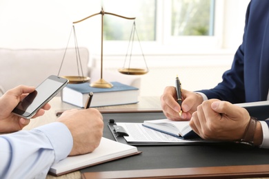 Lawyer working with client at table in office, focus on hands