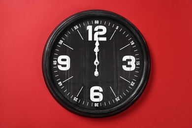 Photo of Modern black clock on red background, top view