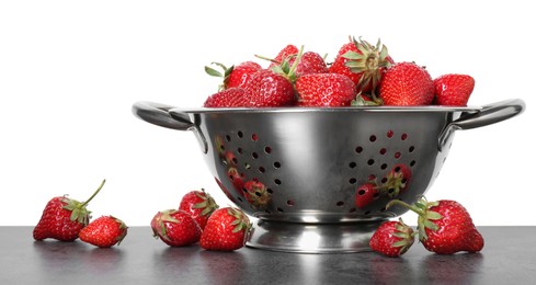 Photo of Metal colander with fresh strawberries on grey table against white background