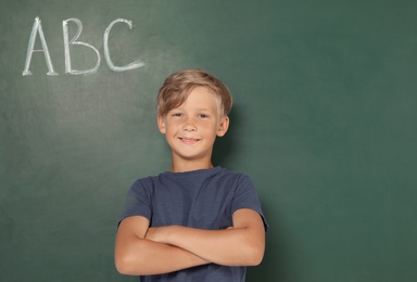 Photo of Little school child near chalkboard with letters ABC