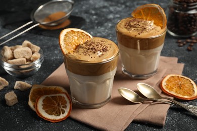 Photo of Glasses of delicious dalgona coffee with ingredients on grey textured table