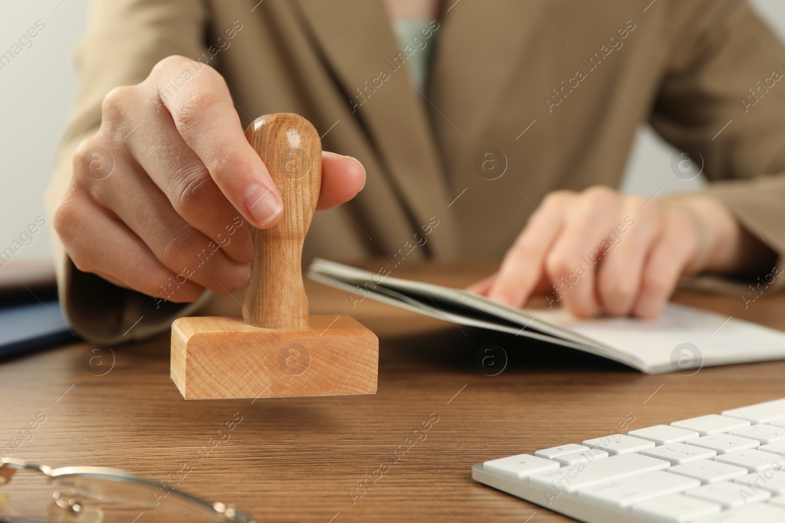 Photo of Woman with stamp and passport at wooden table, closeup