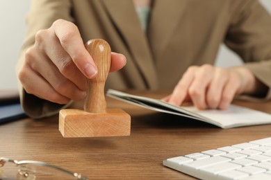 Photo of Woman with stamp and passport at wooden table, closeup