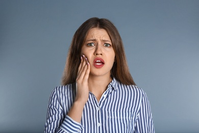 Photo of Woman suffering from toothache on grey background