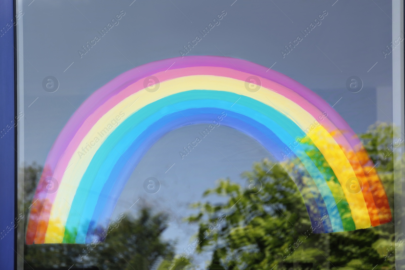 Photo of Painting of rainbow on window, view from outdoors. Stay at home concept