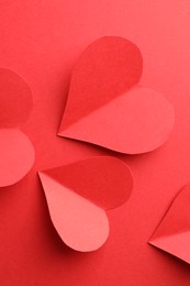 Paper hearts on red background, flat lay