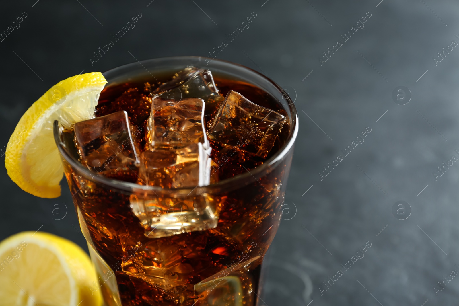 Photo of Glass of refreshing soda water with ice cubes and lemon slice on dark background, closeup