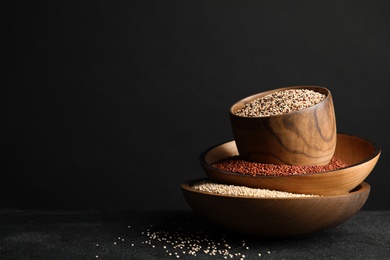 Photo of Composition with different types of quinoa on table against black background. Space for text