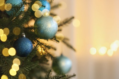 Christmas tree decorated with light blue festive balls on blurred background, closeup. Space for text