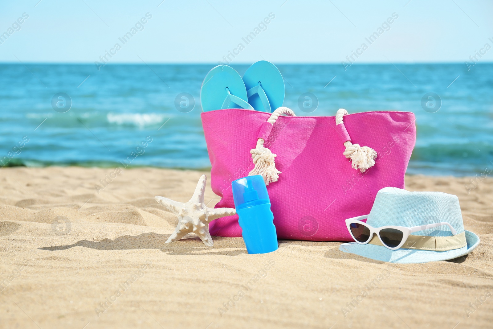 Photo of Stylish beach accessories on sand near sea. Space for text