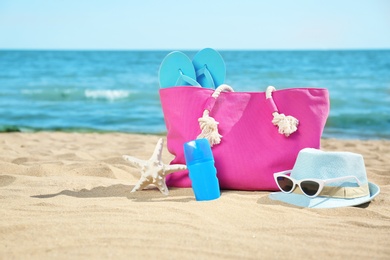 Photo of Stylish beach accessories on sand near sea. Space for text