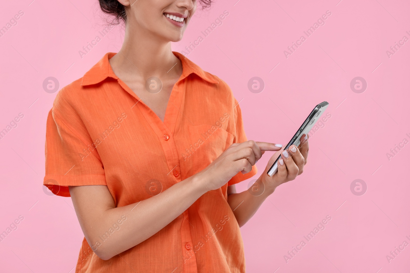 Photo of Woman sending message via smartphone on pale pink background, closeup