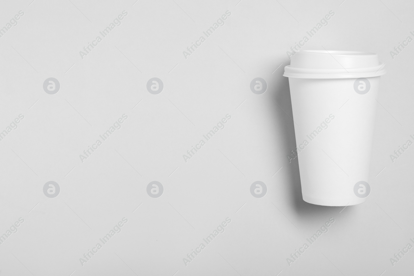 Photo of Takeaway paper coffee cup on light grey background, top view. Space for text