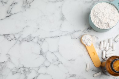 Photo of Amino acid pills and powder on white marble table, flat lay. Space for text