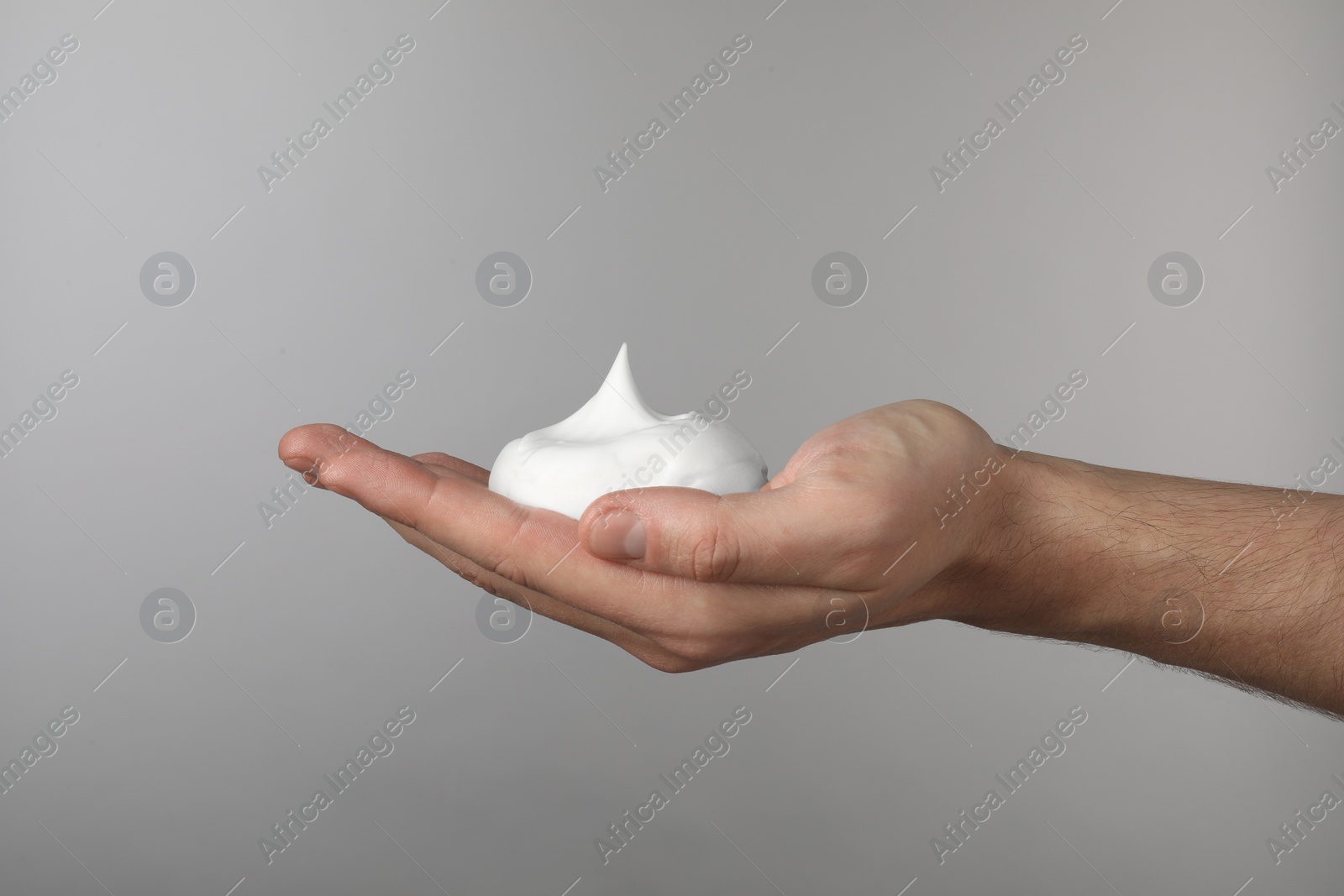 Photo of Man holding shaving foam on light grey background, closeup