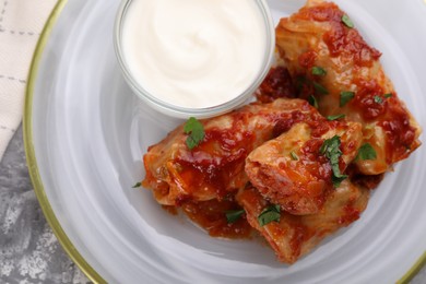 Photo of Delicious stuffed cabbage rolls served with sour cream on grey table, top view