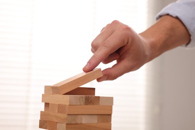 Photo of Playing Jenga. Man Building tower with wooden blocks, closeup