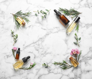 Flat lay composition with bottles of natural tea tree oil and space for text on white marble background