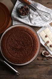 Delicious homemade sponge cake and different kinds of chocolate on wooden table, flat lay