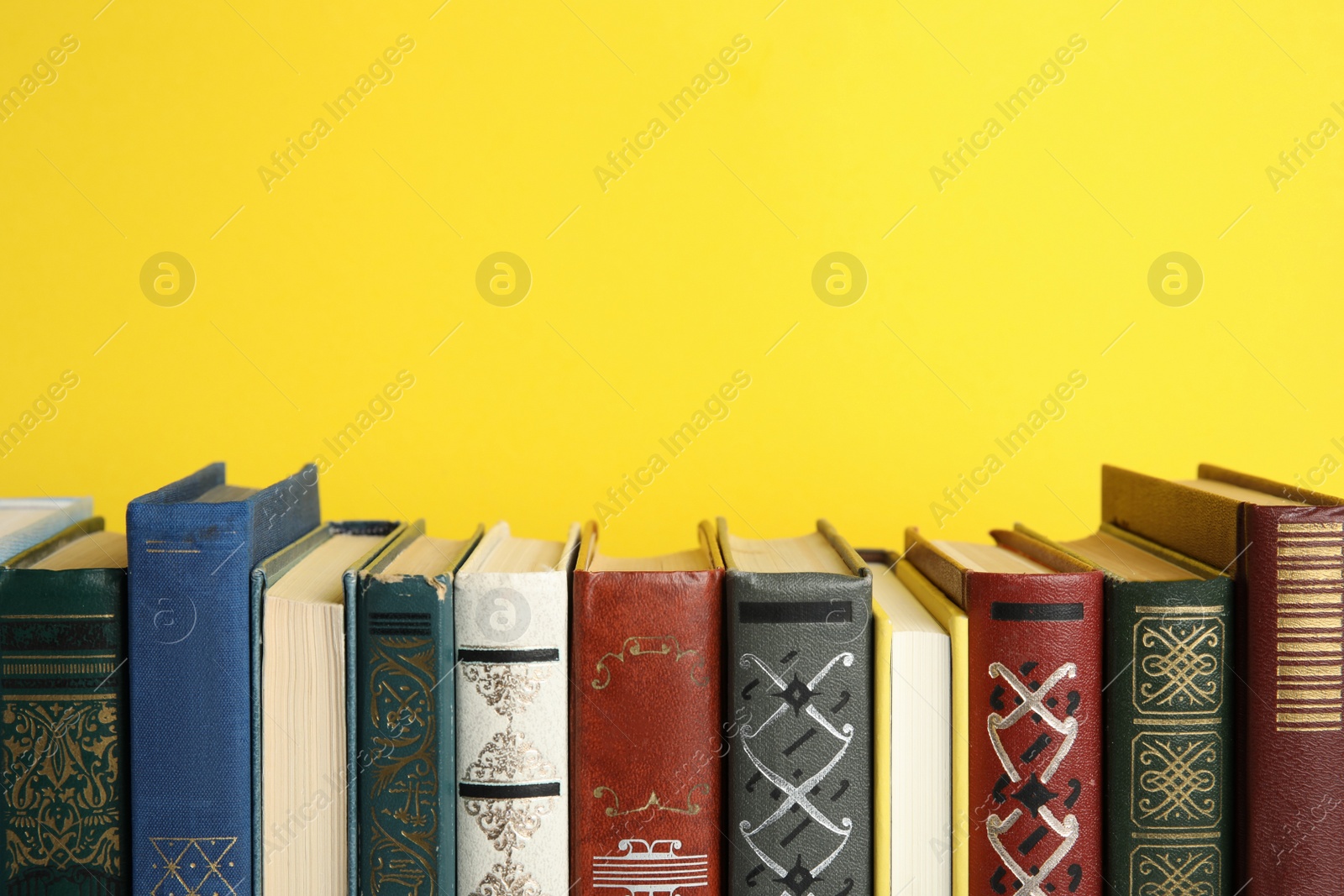 Photo of Collection of old books on yellow background, space for text