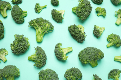 Photo of Fresh tasty broccoli on turquoise background, flat lay