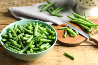 Photo of Fresh green beans in bowl on wooden table, closeup. Space for text