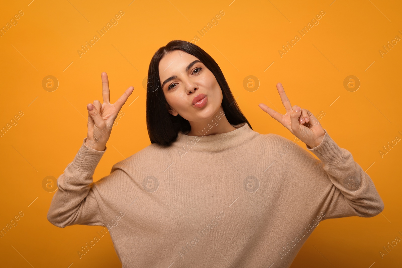 Photo of Beautiful young woman blowing kiss on orange background