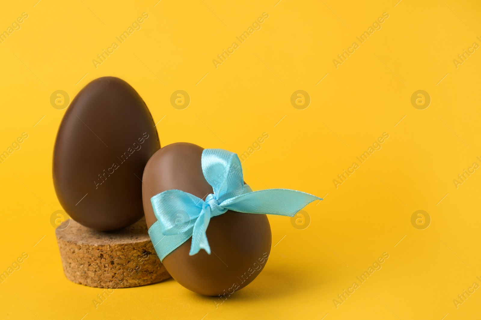 Photo of Tasty chocolate eggs on orange background. Space for text
