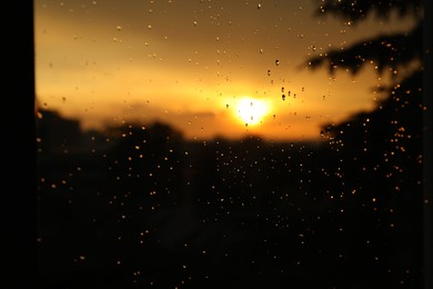 Photo of Blurred view of beautiful sunset through window with condensate drops