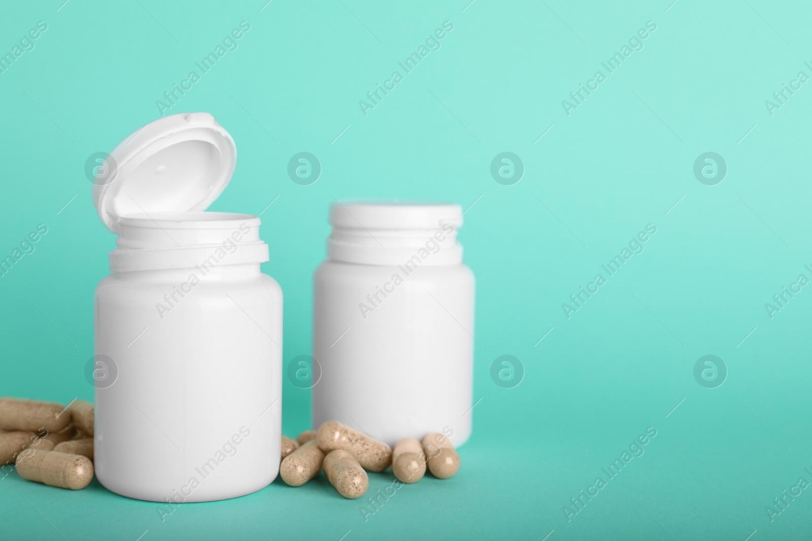 Photo of Gelatin capsules and bottles on turquoise background, space for text