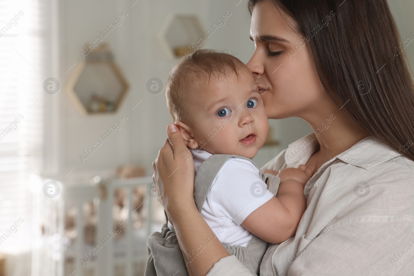 Photo of Happy young mother with her baby in nursery. Space for text