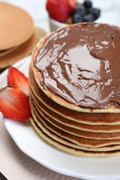 Photo of Tasty pancakes with chocolate paste and strawberries on table, closeup