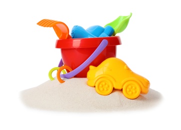 Plastic beach toys on pile of sand, white background