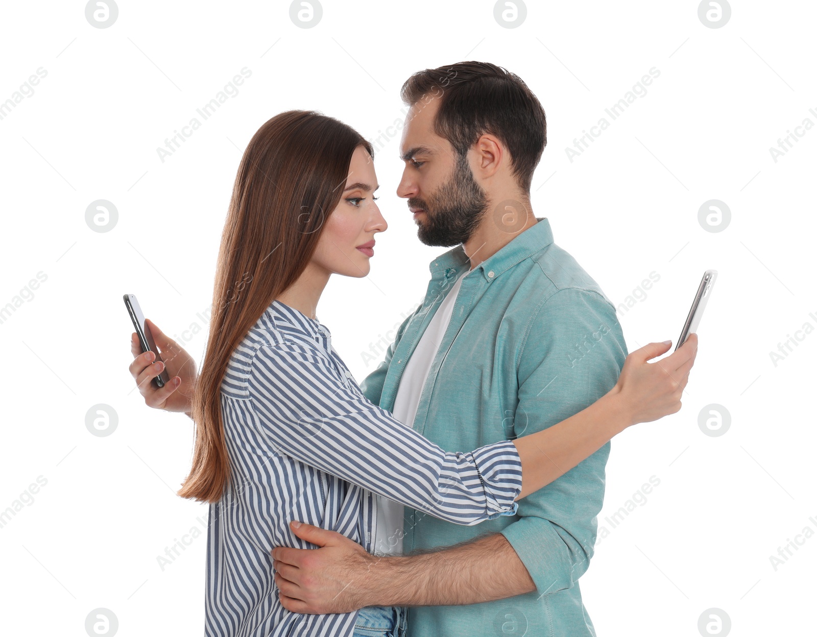 Photo of Couple addicted to smartphones hugging on white background. Relationship problems