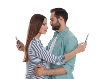 Photo of Couple addicted to smartphones hugging on white background. Relationship problems