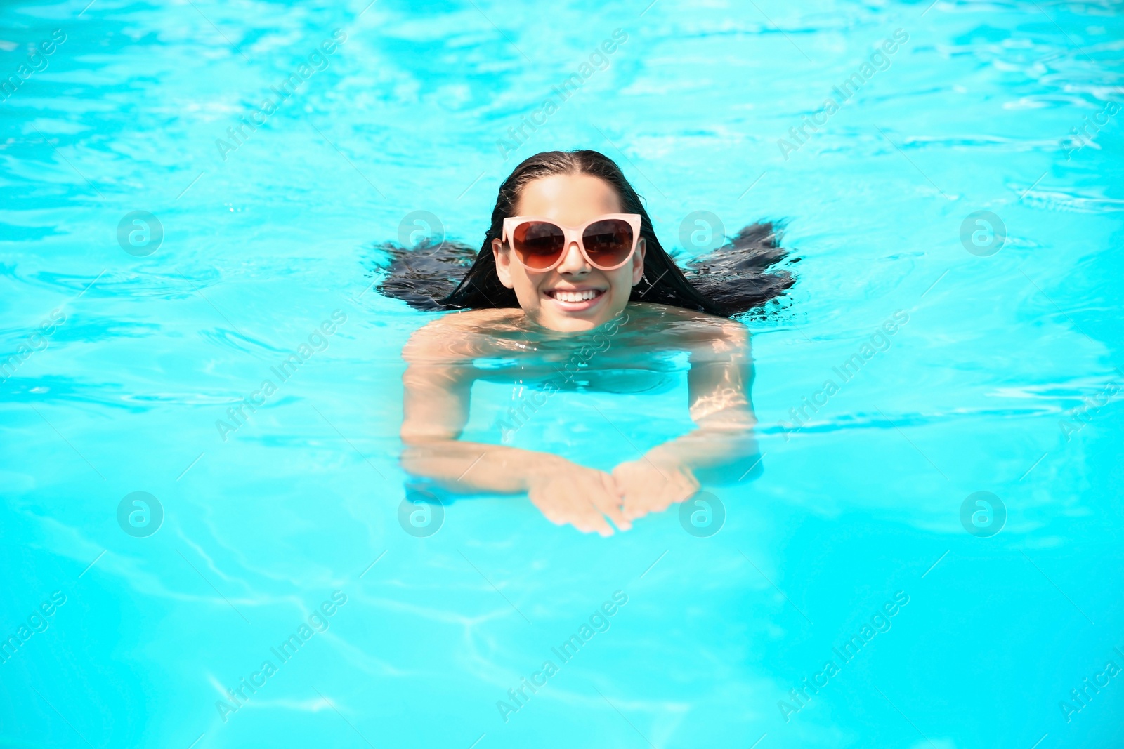 Photo of Beautiful young woman swimming in blue pool