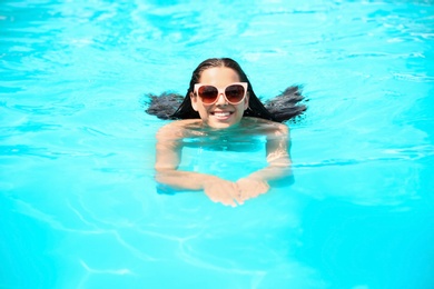 Photo of Beautiful young woman swimming in blue pool