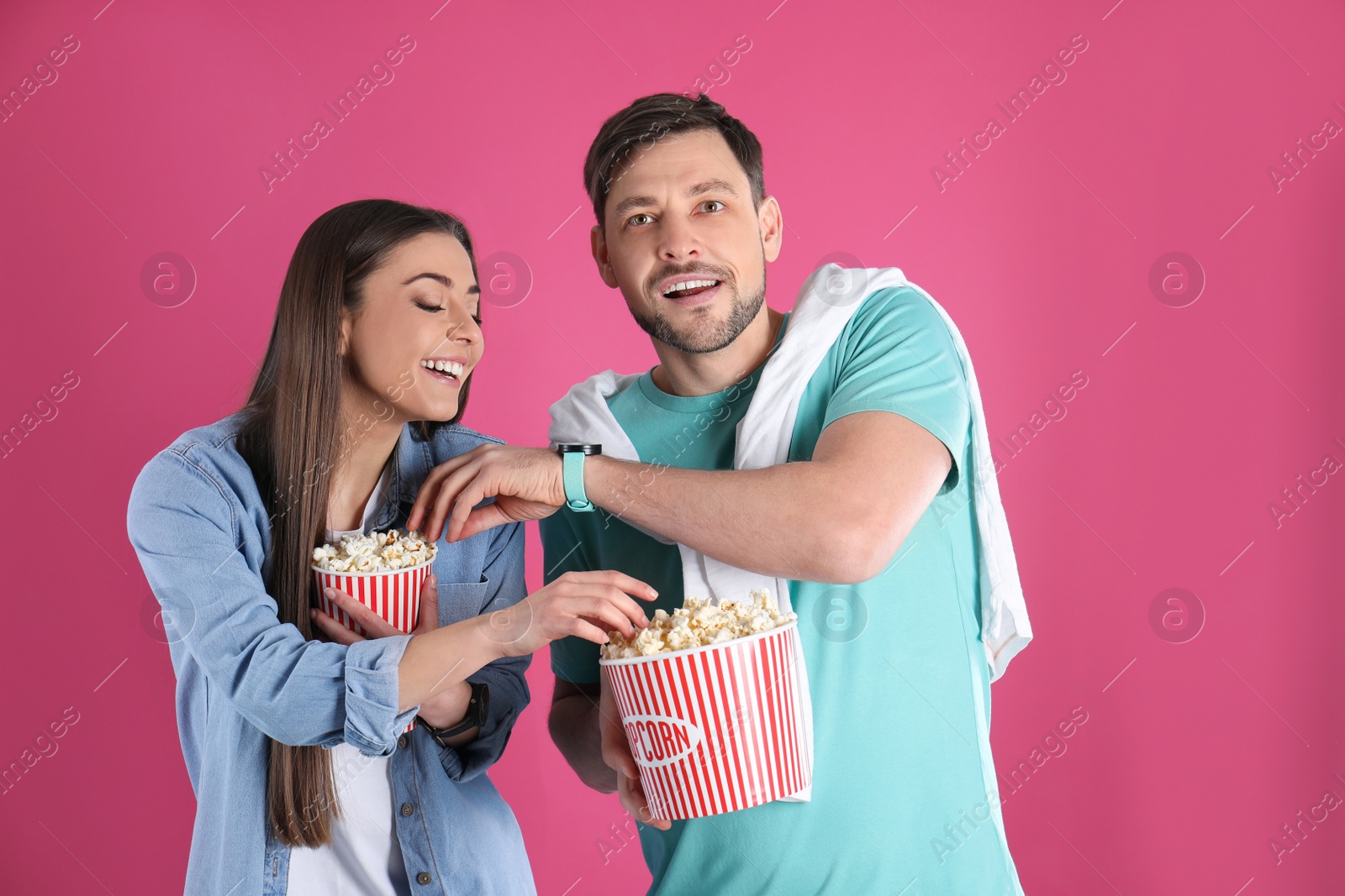 Photo of Couple with tasty popcorn on color background