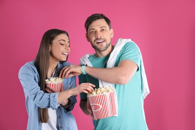 Couple with tasty popcorn on color background
