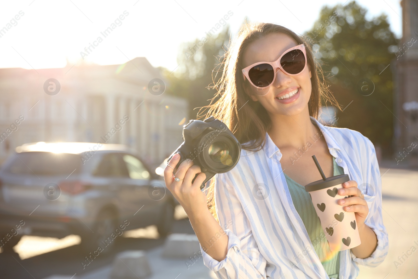 Photo of Young photographer with professional camera and drink outdoors. Space for text