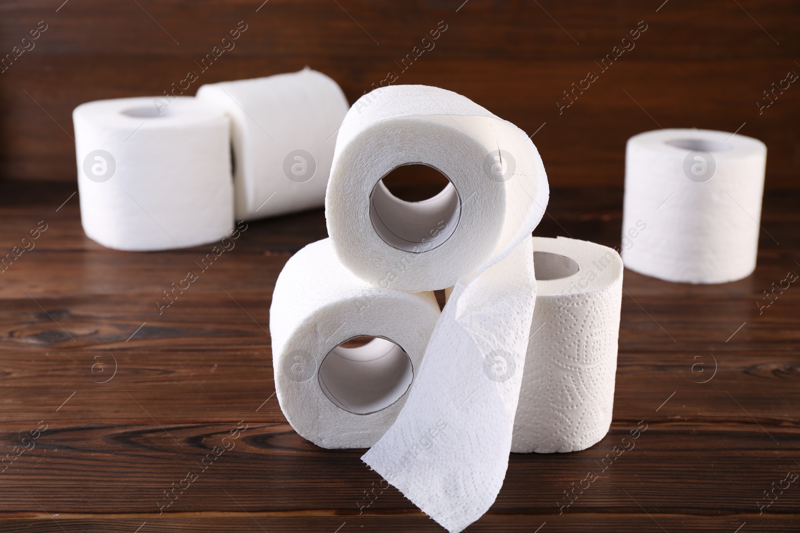 Photo of Many soft toilet paper rolls on wooden table, closeup