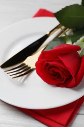 Beautiful place setting with dishware and rose for romantic dinner on white wooden table, closeup