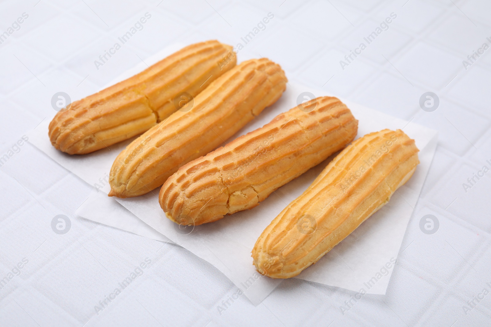 Photo of Four delicious eclairs on white checkered table