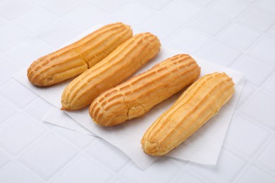 Photo of Four delicious eclairs on white checkered table