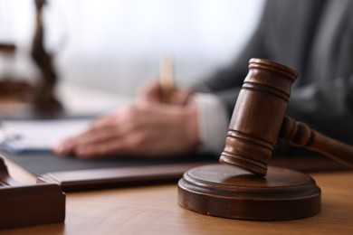 Notary writing notes at wooden table in office, focus on gavel