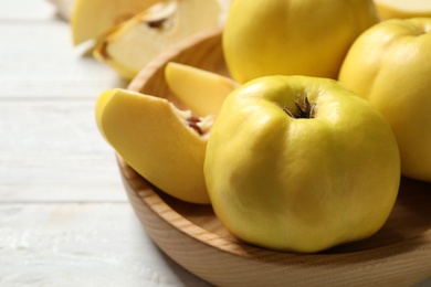 Photo of Fresh ripe organic quinces on white wooden table, closeup