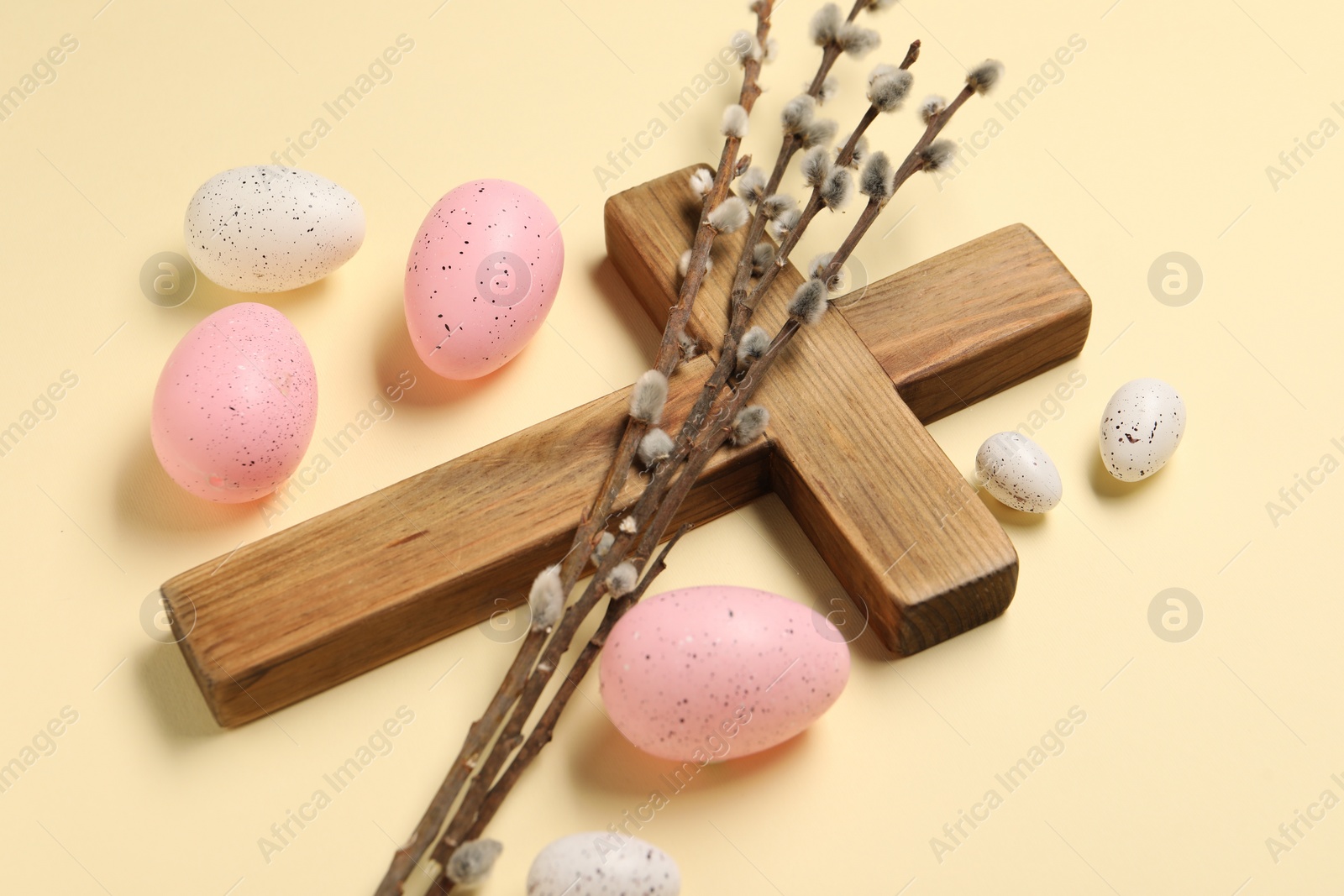 Photo of Wooden cross, painted Easter eggs and willow branches on beige background