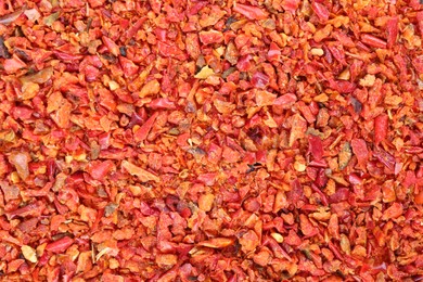 Photo of Aromatic spice. Red chili pepper flakes as background, top view