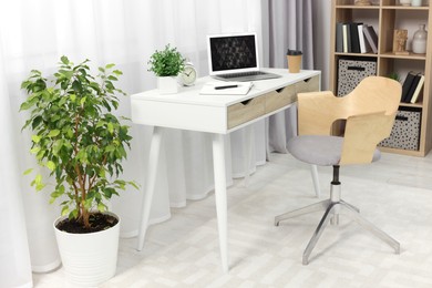 Photo of Workplace with modern laptop on desk and comfortable chair at home